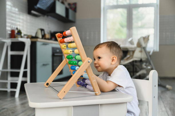 这孩子正在学数数。一个孩子用算盘学习数学的画像。一岁半的婴儿图片下载