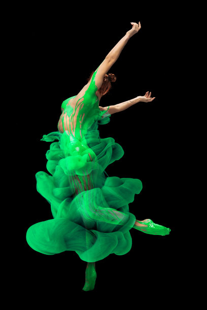年轻感性的女人的肖像覆盖着绿色的油漆和染料飞溅的姿势，跳舞孤立在黑色的背景图片下载