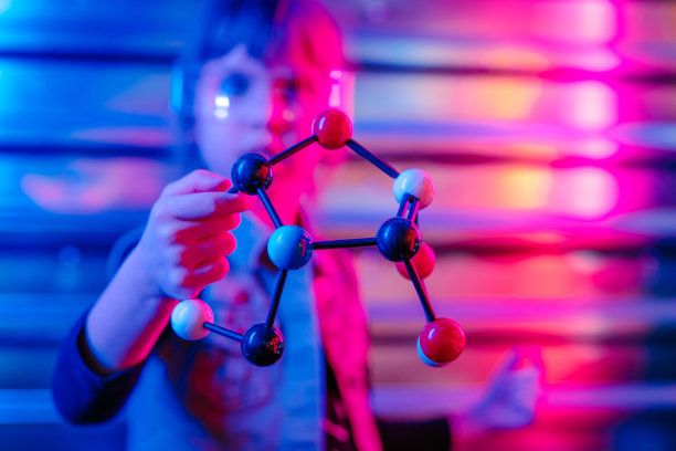 小女孩拿着分子模型在五彩缤纷的霓虹灯背景下图片下载