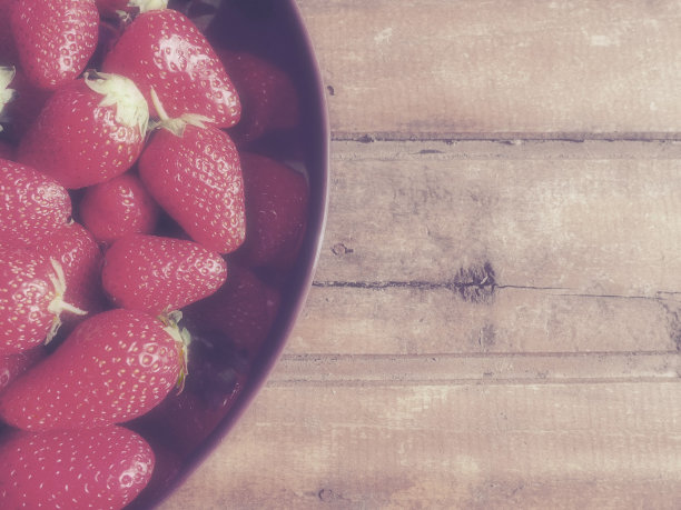草莓盘，木制背景。深色陶瓷盘子和美味的红色大草莓园。健康的食物，维他命和素食。有食物的静物。副本的空间。平的。图片下载