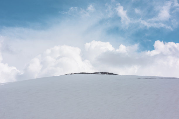 美丽的风景，巨大的雪山圆顶和岩石顶部下大郁郁葱葱的白云蓝天。令人敬畏的山景，在多变的天气中，中心是圆顶状的高雪山图片下载