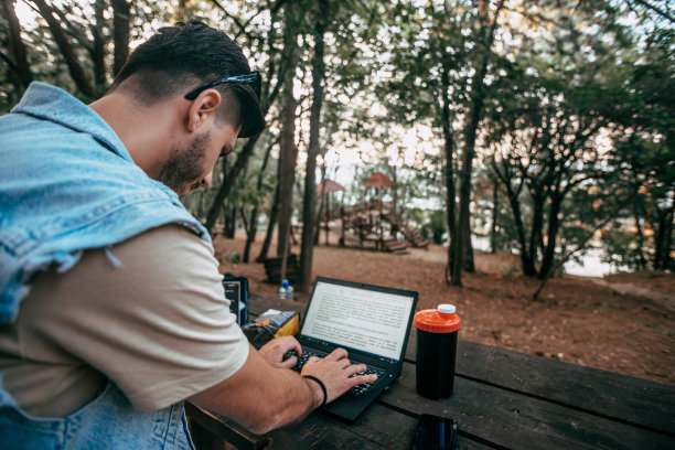 自由职业者坐在大自然的木桌上，在笔记本电脑上工作图片下载