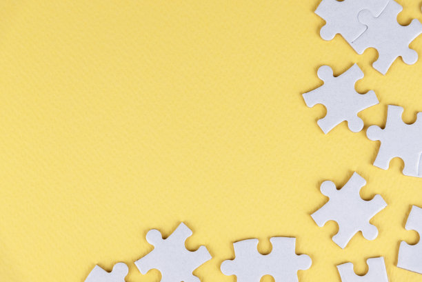 空白的白色拼图与一些缺失的碎片在软黄色背景。图片下载