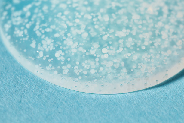 光滑磨砂洗刷凝胶滴在蓝色背景上。图片下载