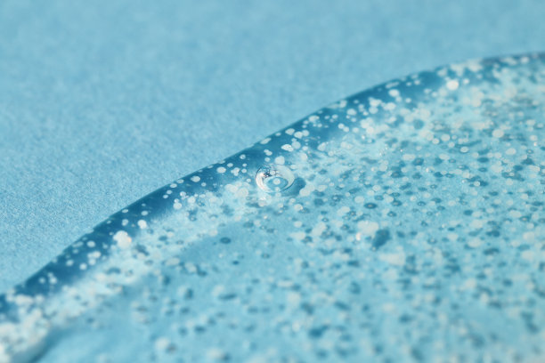 光滑磨砂洗刷凝胶滴在蓝色背景上。图片下载