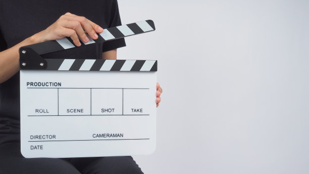 女人坐在椅子上，手握拍板或电影板。它适用于视频制作，电影，电影行业的白色背景。图片下载