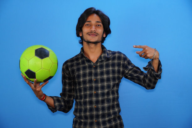 年轻英俊的球员拿着黑色和黄色的足球，露出惊讶的表情，恐惧和兴奋的表情。图片下载