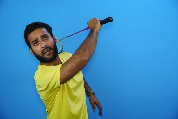 男子在蓝色背景下打羽毛球图片下载