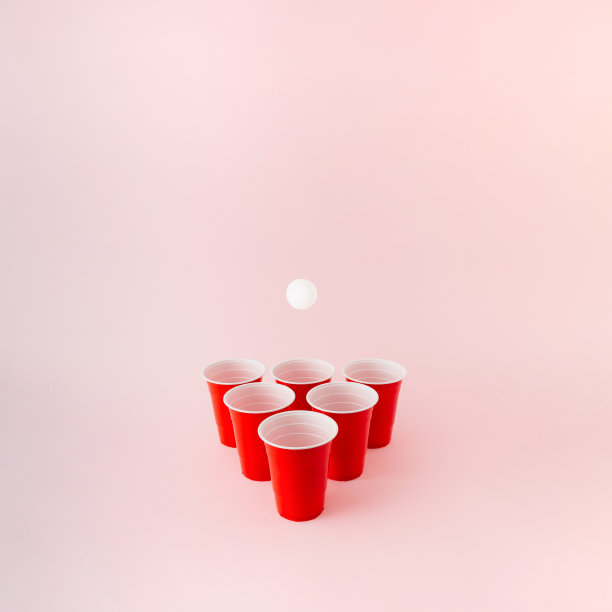六个红色塑料啤酒桌球杯，白色的球在上面盘旋。图片下载