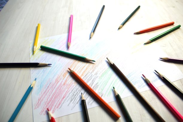 五颜六色的铅笔堆在彩色的白纸上图片下载