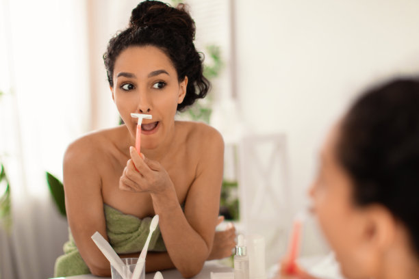 脸毛脱毛。漂亮的年轻女士在毛巾剃她的上唇在浴室的镜子，复印空间图片下载