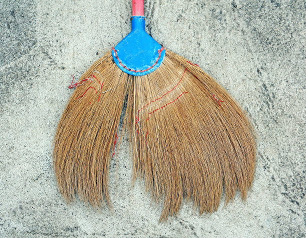 水泥地上有一把坏掉的泰国扫帚。图片下载