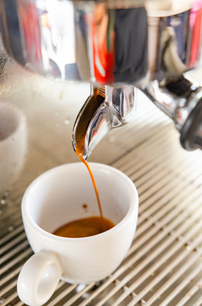 浓缩咖啡从咖啡机倒入一杯白色咖啡。图片下载