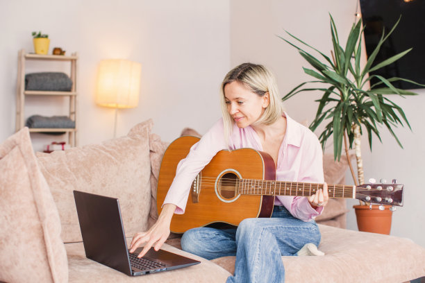 中年妇女练习和学习如何在笔记本电脑上弹吉他图片下载
