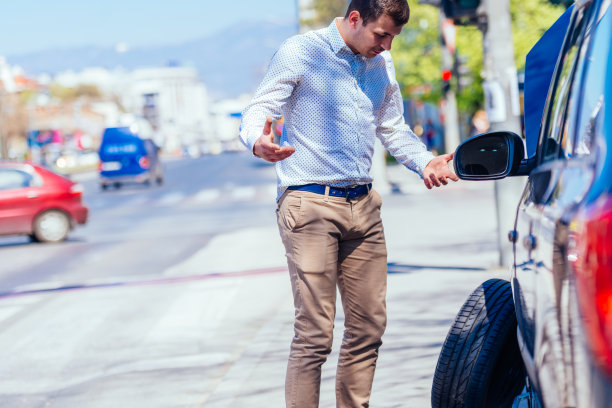 在一个阳光明媚的日子里，一位满身是汗、疲惫不堪的年轻企业家在换车胎时擦着额头上的汗水图片下载