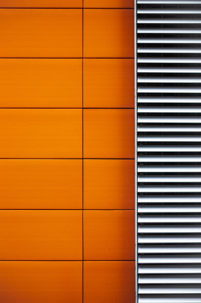 现代建筑明亮的橙色瓷砖外观与金属格栅形成鲜明对比图片下载