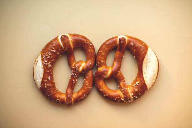 两个新鲜出炉的椒盐卷饼特写，孤立在米色的背景上图片下载