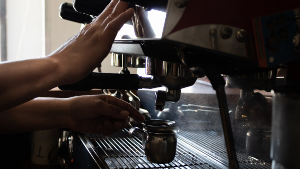 墨西哥图卢姆的一家咖啡店里，一名年轻女子用手将咖啡倒进两个咖啡杯里。图片下载