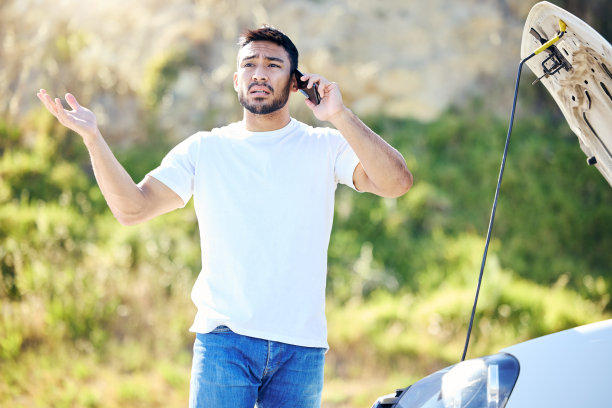 这张照片拍摄的是一名年轻英俊的男子在遭遇汽车故障后与路边救援人员通电话图片下载