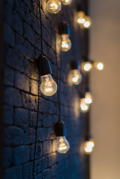 在黑色墙壁的背景上，白炽灯发出耀眼的光芒，这是一个室内摄影工作室阁楼的装饰元素图片下载