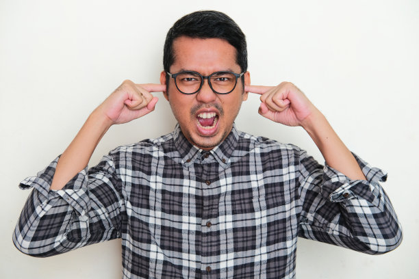 亚洲成年男子尖叫愤怒的肖像，同时用手指关闭他的耳朵图片下载