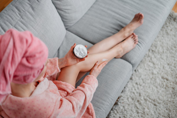 年轻女子在皮肤上涂乳液图片下载