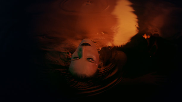 水下冥想。迷人的女人从深色、金色的水中浮现图片下载