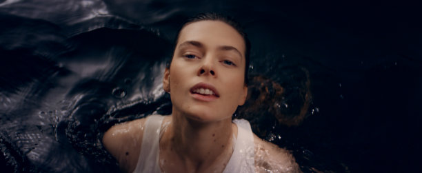 从黑暗的水中浮现出一个娇弱的女人。浸湿她那湿漉漉的长发。自然美容护理隐喻图片下载