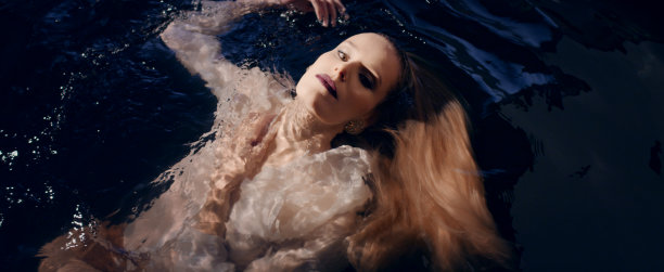 脆弱的女人漂浮在黑暗的水面上。自然美容护理隐喻图片下载