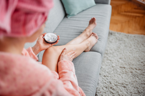 年轻女子在皮肤上涂乳液图片下载