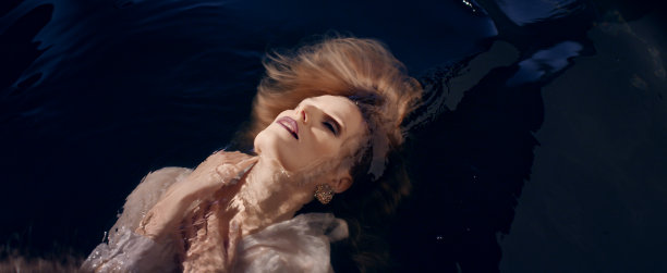 脆弱的女人漂浮在黑暗的水面上。自然美容护理隐喻图片下载