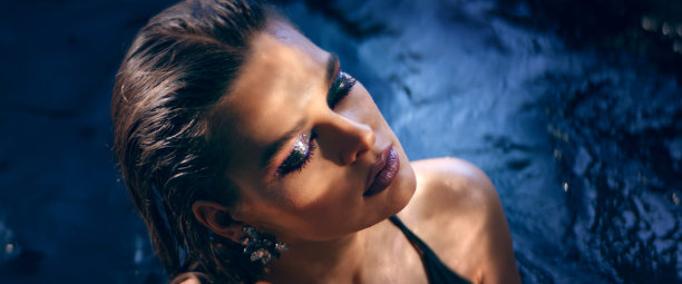 优雅的女人从水中浮现。用摄影机调情。美容护理的比喻图片下载