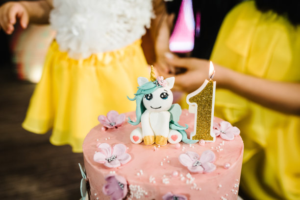 一年的生日蛋糕。蛋糕上装饰着独角兽、蜡烛和鲜花。节日甜点的概念。图片下载