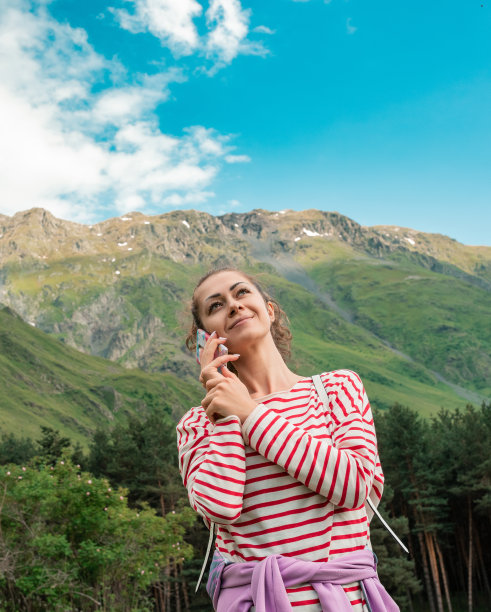 自由旅行者女人站在手机在手，享受美妙的自然。图片下载