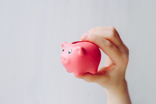 近距离的观点，年轻的孩子手里拿着可爱的粉红色的小储蓄罐，白色的背景，大量的复制空间。图片下载