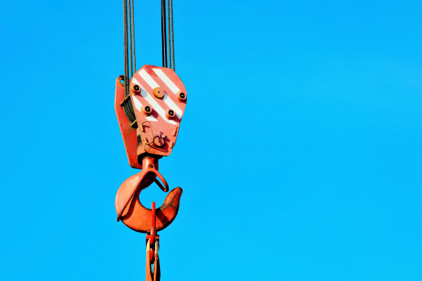 吊钩与金属缆绳衬托蓝天。卸货或装载货物图片下载