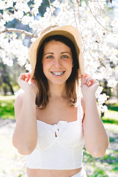 白人女性的垂直肖像，穿着白色的衣服，戴着牙箍。图片下载