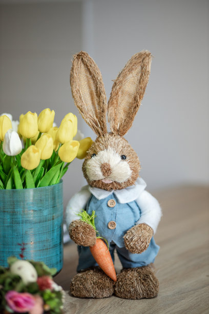 可爱的复活节兔子拿着胡萝卜，旁边是美丽的郁金香图片下载