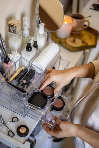 特写女性的手把豪华化妆品放进丙烯酸盒与抽屉存储组织图片下载