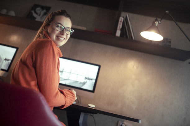 一个笑眯眯的程序员坐在电脑前的照片。图片下载
