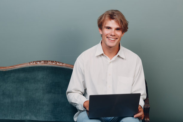 肖像年轻男子坐在笔记本电脑在工作室。图片下载