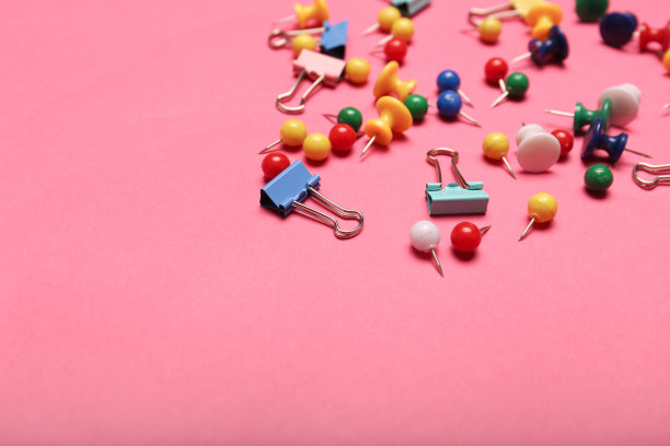粉红色背景上的彩色回形针图片下载