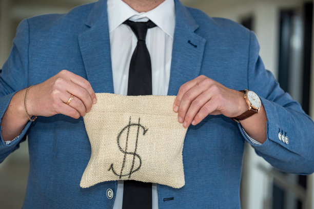 一个男人穿着优雅的经典西装，打着领带，手里拿着一大袋他赚来的钱。图片下载