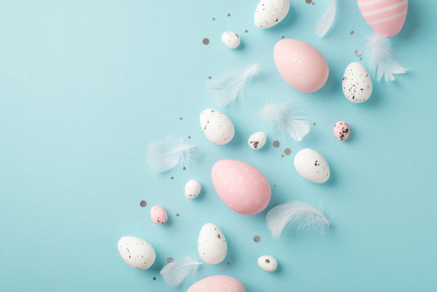 复活节装饰羽毛亮片粉红色和白色复活节蛋的俯视图照片在孤立的淡色蓝色背景与copyspace图片下载