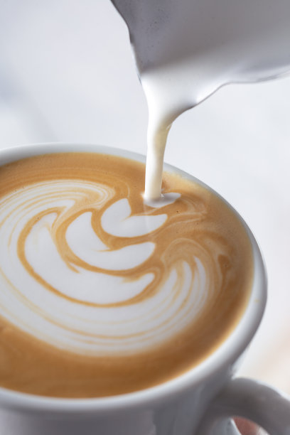 咖啡师将拿铁泡沫倒在咖啡、浓缩咖啡上，创造出完美的卡布奇诺图片下载