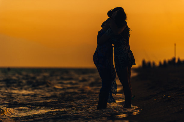 女人在夏天的裙子剪影，拥抱在海边图片下载