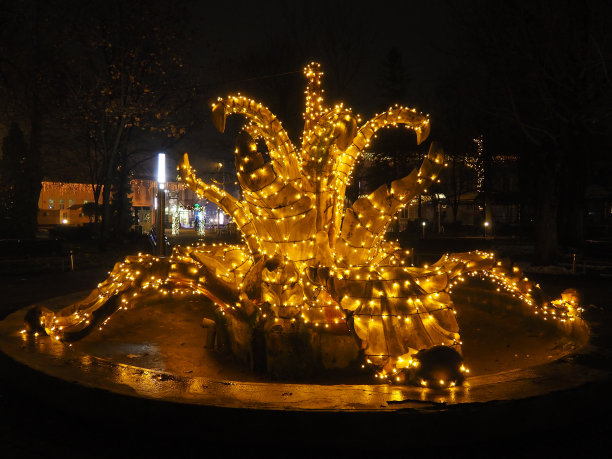 到达米特罗维察,塞尔维亚。冬天的喷泉。圣诞节的晚上。美丽的圆形突出。金黄色和黄色在黑暗中闪烁。恭贺新禧，圣诞快乐。城市街道装饰图片下载