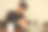 一名黑发胡须的年轻男性一边看手表一边戴着耳机合上办公桌上的笔记本电脑，灰色背景下他的办公桌上放着一台笔记本电脑——关机或关机时间图片下载