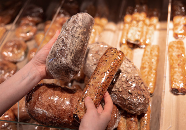 在超市柜台前，一位妇女手里拿着面包。图片下载