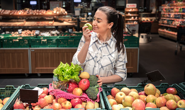 一位年轻女子在超市挑选水果和蔬菜。图片下载